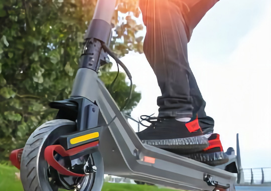 Man carrying a coffee and folded e-scooter down stairs